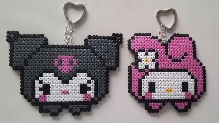 two pixelated animal key chains are shown on a white surface, one is pink and the other is black