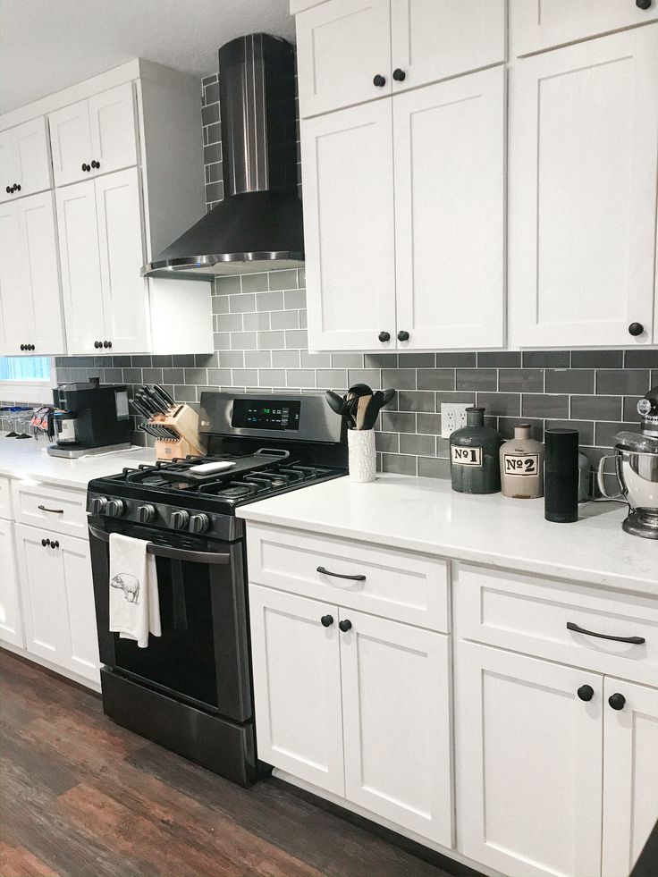 a kitchen with white cabinets and black appliances