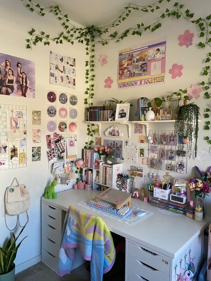 a desk with many pictures and plants on the wall above it, along with other office supplies