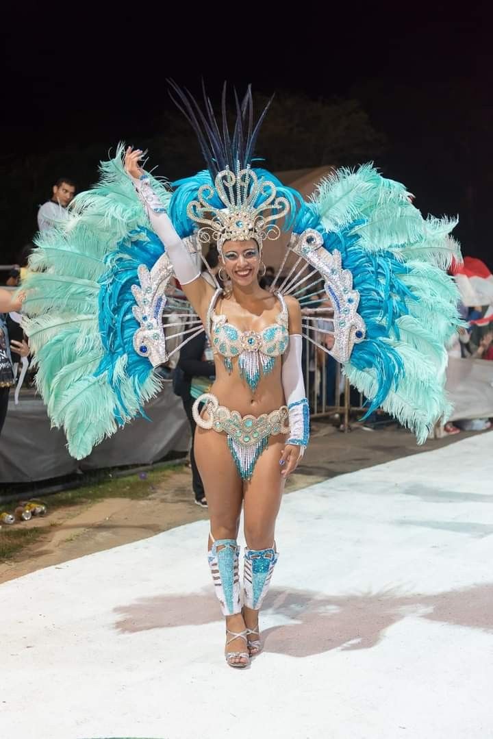 a woman in a blue and white costume walks down the runway with her arms outstretched