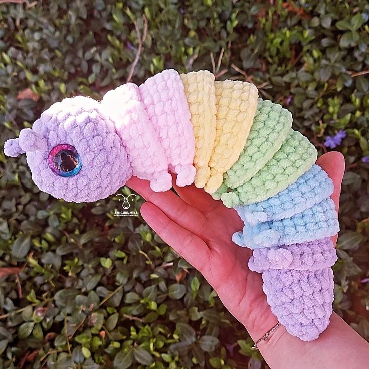 a hand holding a small crocheted caterpillar