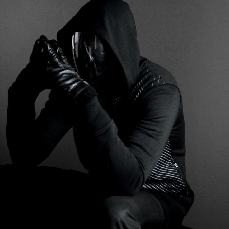 a man in a hoodie sitting down with his hands on his face