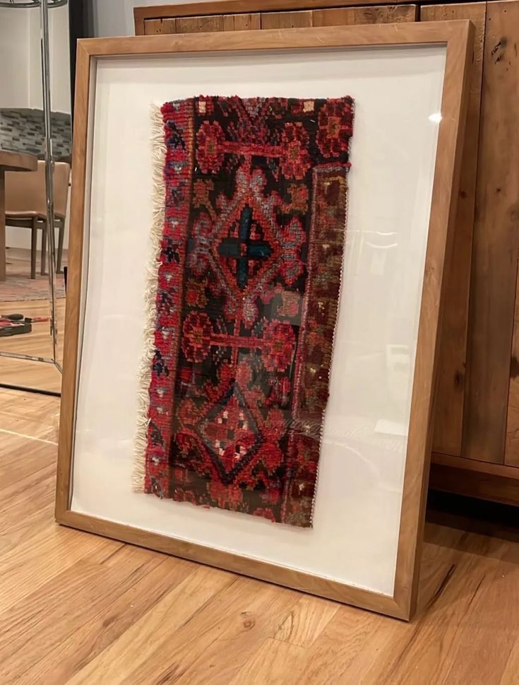 an old rug is in a frame on the floor