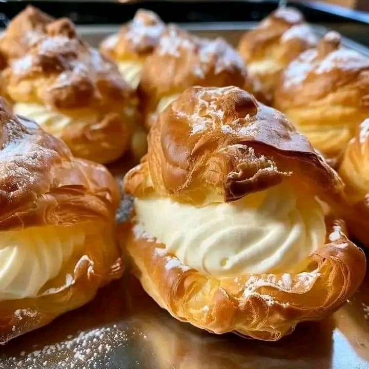 several pastries are sitting on a metal tray with powdered sugar and icing