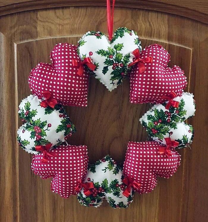 a red and white christmas wreath hanging on the front door with holly decorations around it