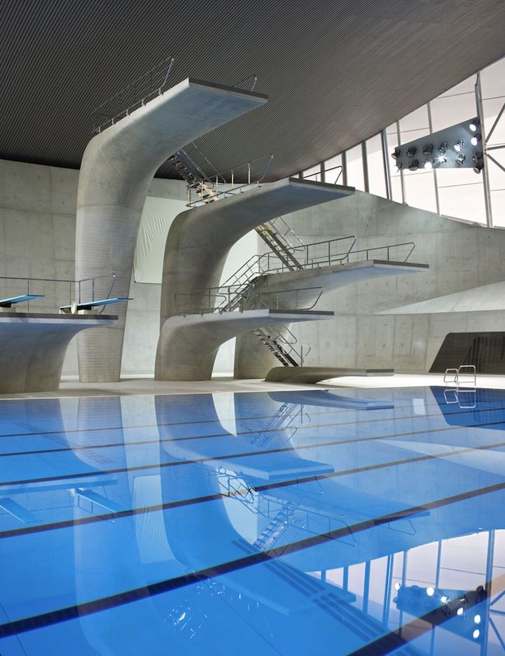 an indoor swimming pool with blue water and large white structures on the wall behind it