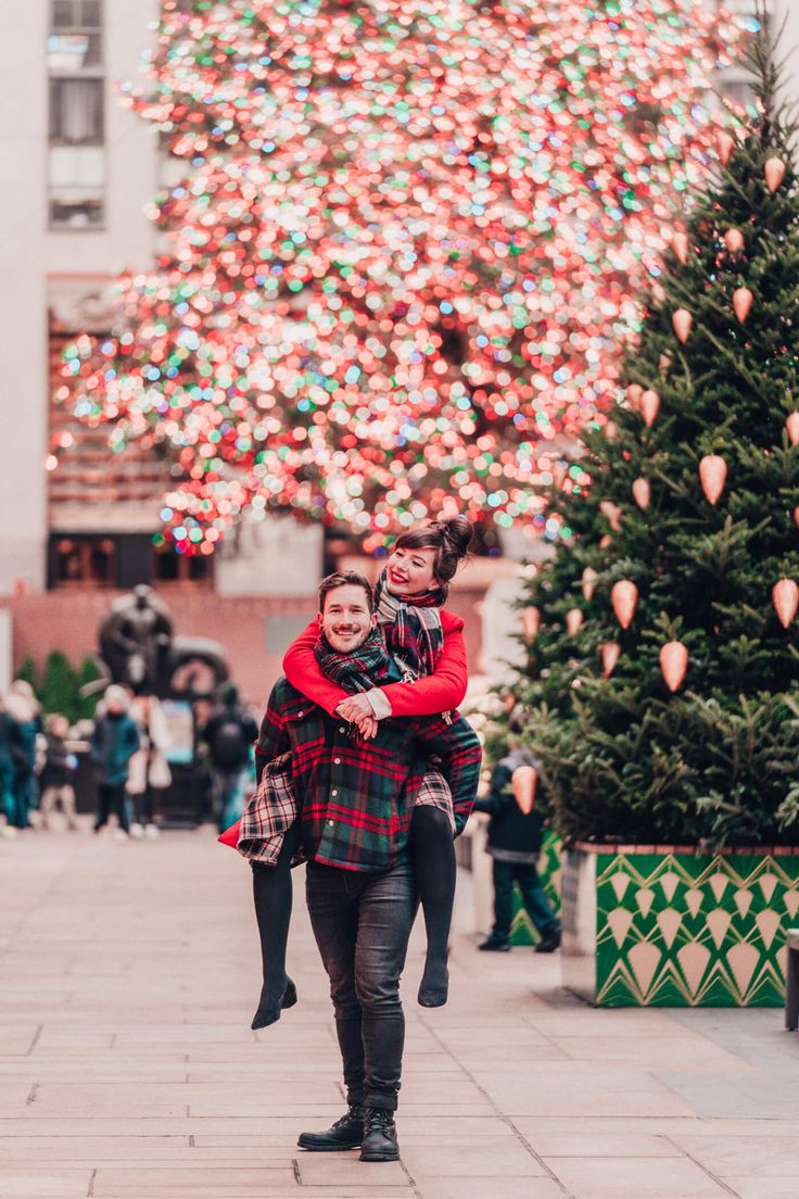 two people walking in front of a christmas tree