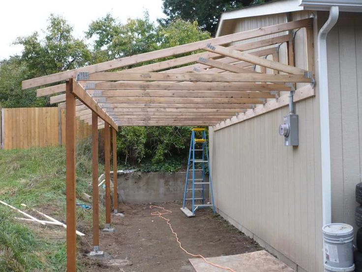 a wooden pergolan is being built in front of a house with a ladder