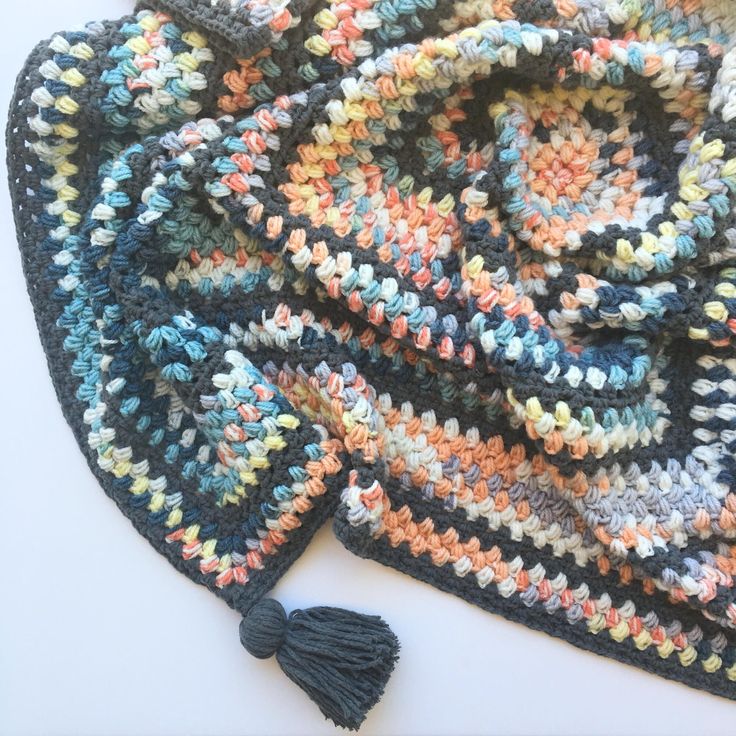 a multicolored crocheted blanket with tassels