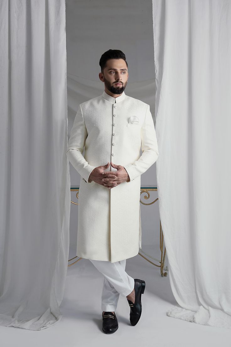 This White Long Sherwani is a stunning choice for your special occasion. Made from printed off-white khaadi silk, it features a silk kurta and cotton pajama for a comfortable fit. Complete your look with the elegant organza Rajastjhani kula (turban) and exude an air of style and sophistication. Elegant Silk Sherwani For Eid, Festive Cotton Sherwani With Naqshi, Festive Cotton Sherwani With Naqshi Embroidery, Festive Cotton Sherwani With Naqshi Details, Elegant Raw Silk Bandhgala For Eid, Elegant Festive Cotton Silk Sherwani, Elegant Sherwani With Dabka On Straight Kurta, Silk Straight Kurta Sherwani For Wedding, Silk Sherwani With Straight Kurta For Wedding