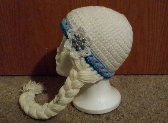 a white knitted hat with braids and flowers on the side, sitting on a mannequin head