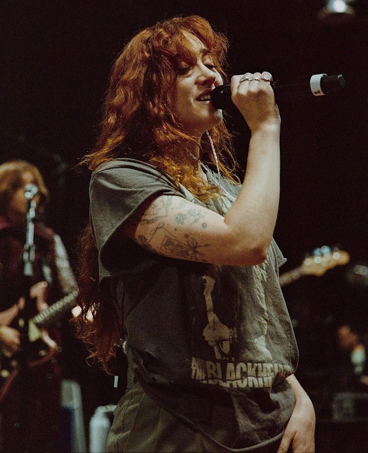 a woman with red hair singing into a microphone