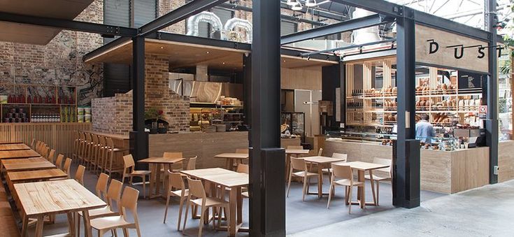 the inside of a restaurant with wooden tables and chairs in front of an open air kitchen