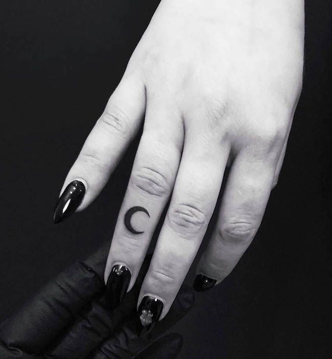 a woman's hand with black and white nail polish on it, holding an object