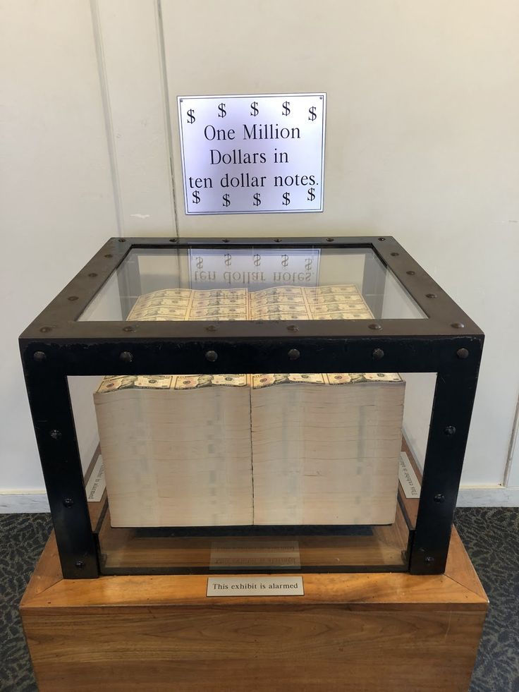 a glass table with two stacks of dollars on it and a sign that says $ 1 million dollars in ten dollar notes