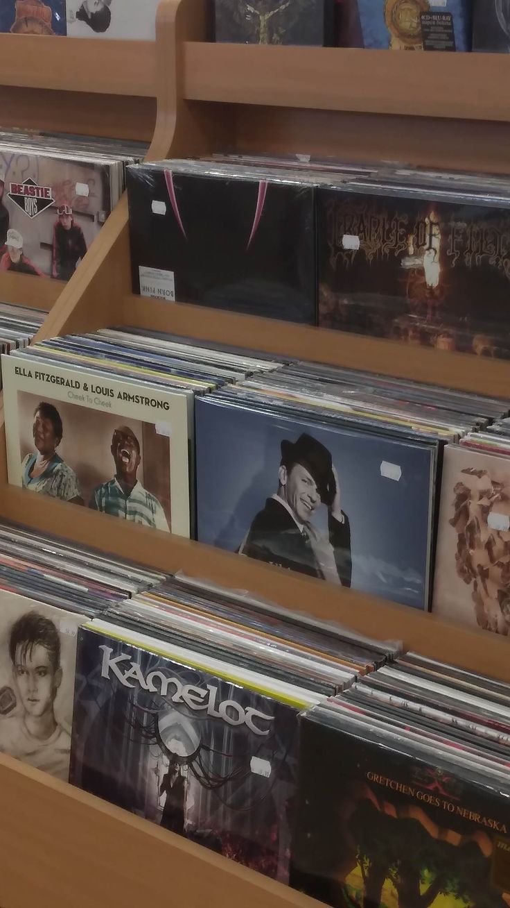 several cd's are stacked on the shelves in a music store, and one is empty