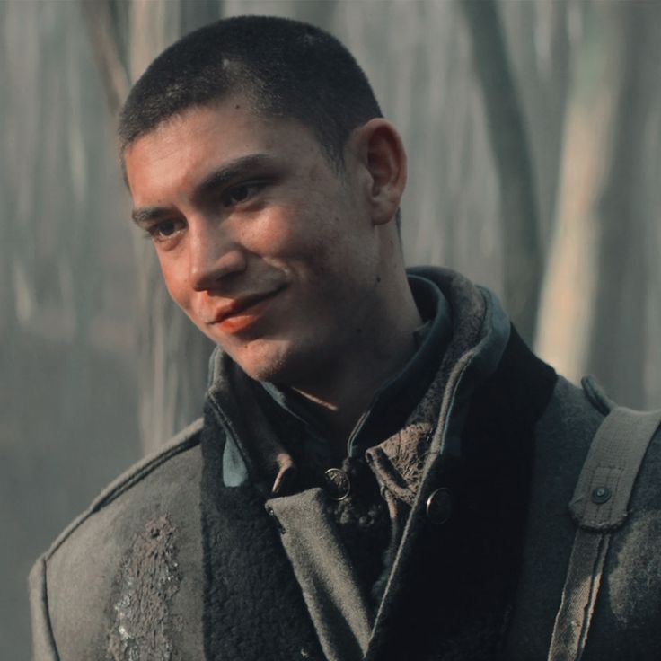 a man in a black jacket standing next to trees