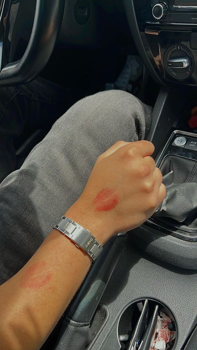 A male arm holding the steering stick of a car is covered with red lipstick kisses. The arm also wears a Casio watch Lipstick Kisses Boyfriend Aesthetic, Secret Couple Picture Ideas, Lipstick Marks On Boyfriend Aesthetic, Red Lipstick Kisses Boyfriend, Secret Bf Pics Snap, Showing Off Nails Pose With Boyfriend, Secret Photos With Boyfriend, Couple Lipstick Mark, Lipstick On Boyfriend Face