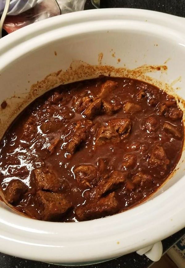 a white crock pot filled with meat and sauce