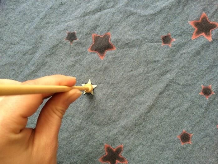 someone is drawing stars on a piece of fabric