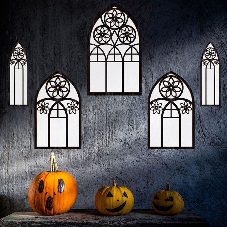 three pumpkins are sitting on a table in front of an arched window with windows