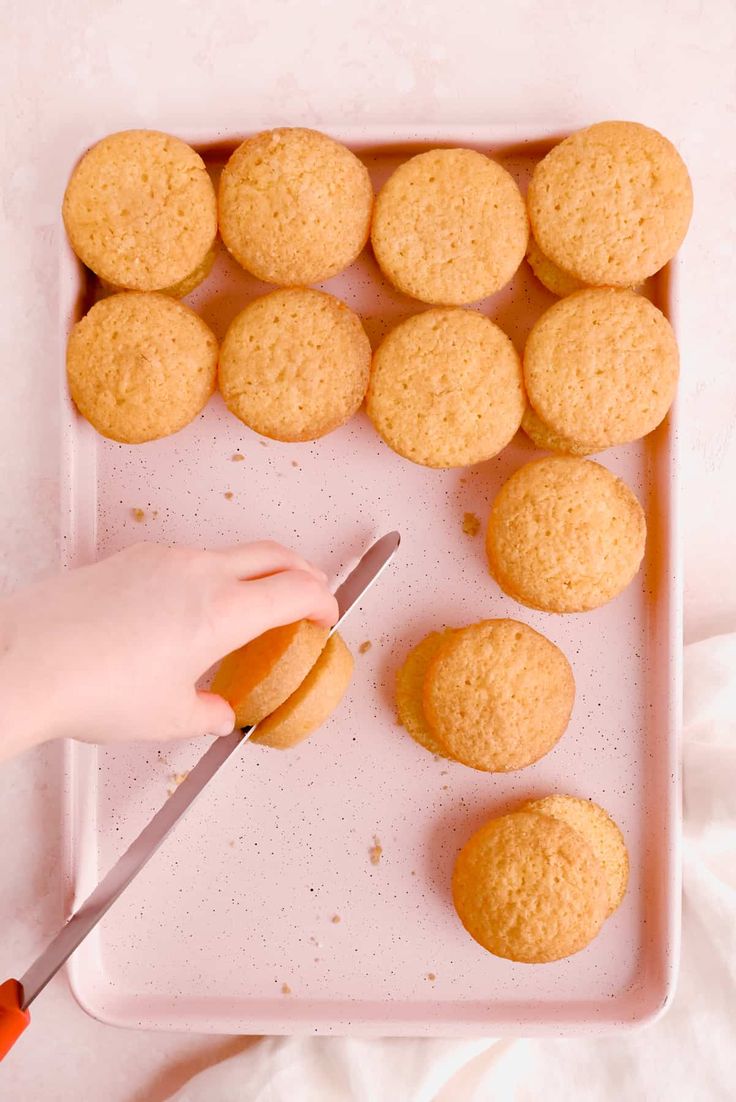 a person is cutting up some cookies on a tray with a knife and oranges