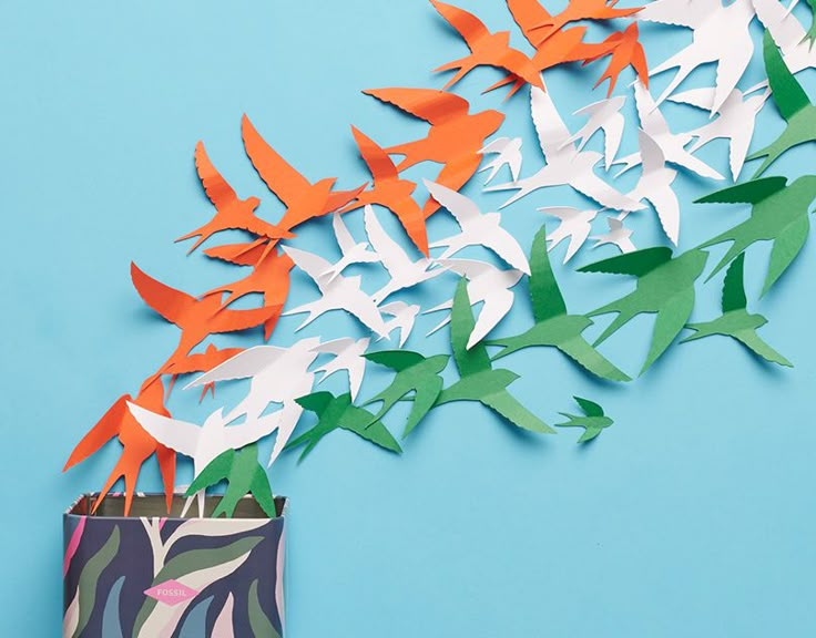 some paper birds are flying out of a bag on a blue background with an origami bird design