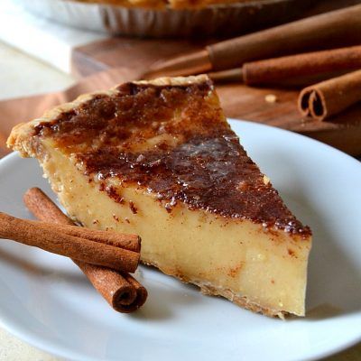 a piece of cheesecake on a plate with cinnamon sticks