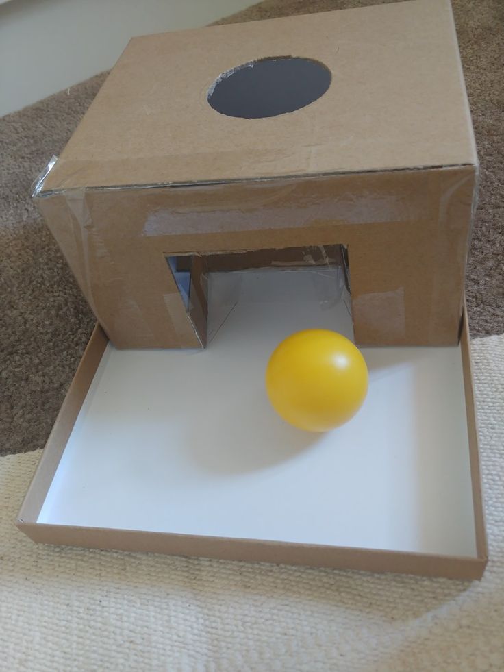 an orange ball is in the middle of a cardboard box with a hole on it