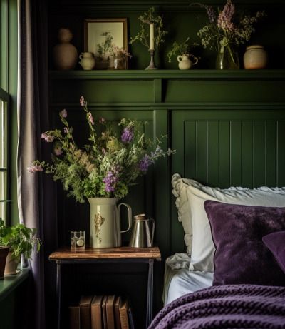 a bedroom with green walls, purple bedding and vases filled with flowers on the nightstand