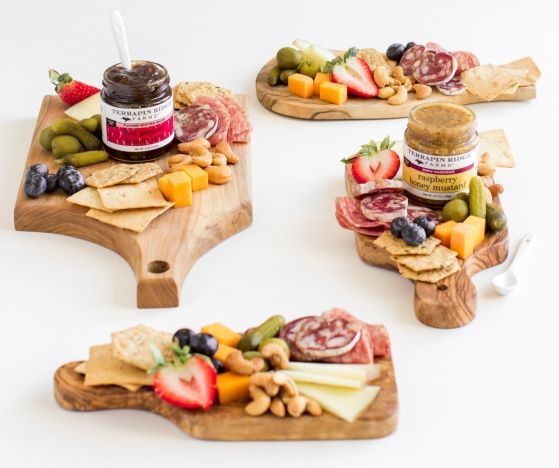 three wooden trays filled with fruit and crackers on top of a white table