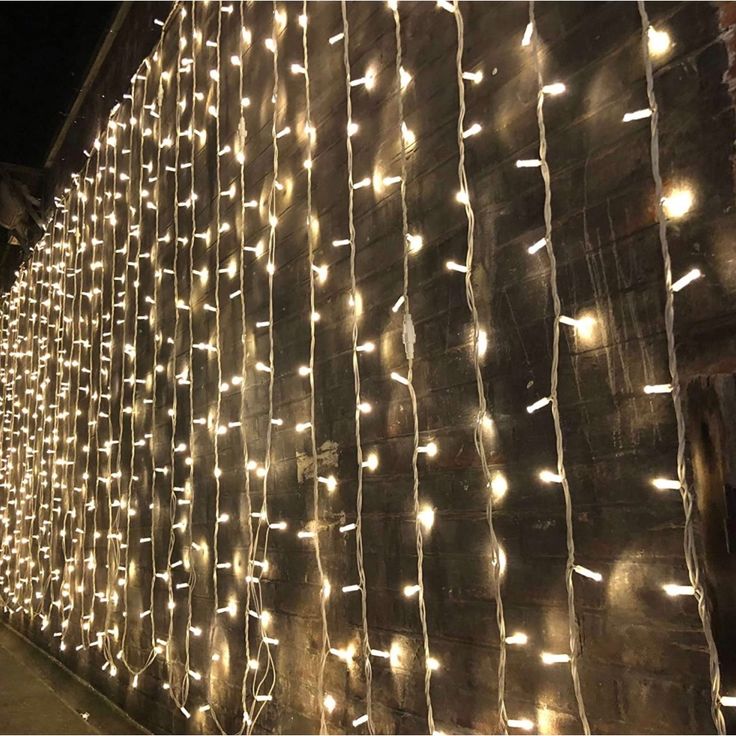 a wall covered in white lights next to a building