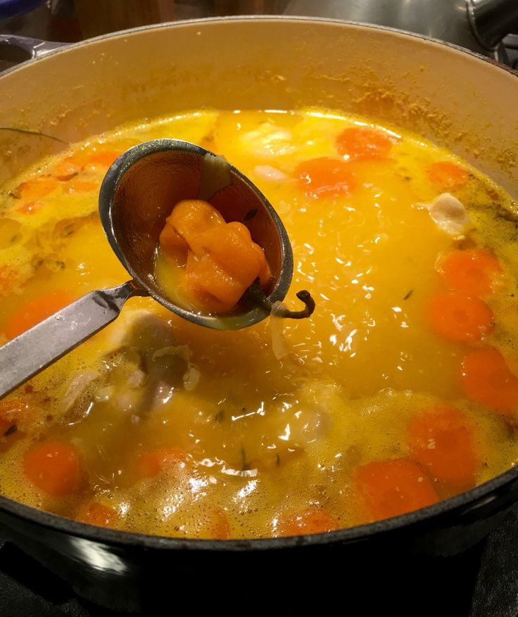 a ladle full of soup with carrots in it