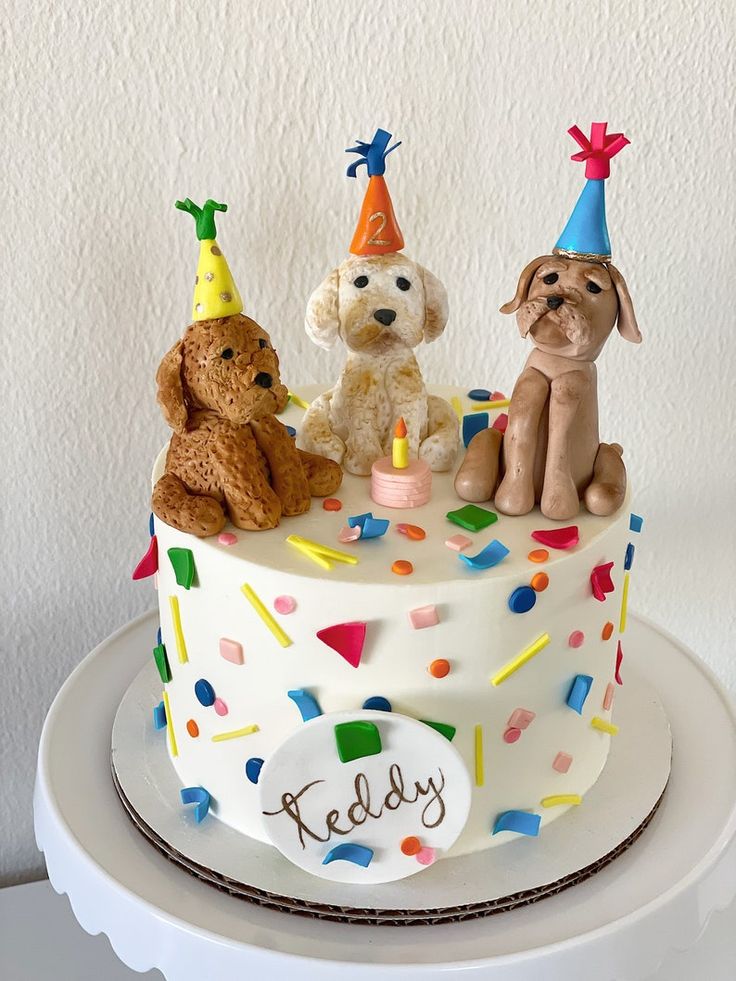 three dogs sitting on top of a birthday cake