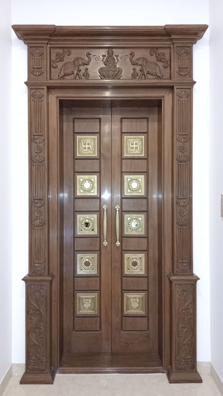 an ornate wooden door with glass inserts on the front and side panels, in a white room