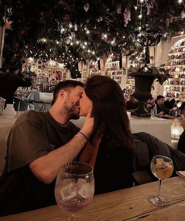 a man and woman sitting at a table kissing