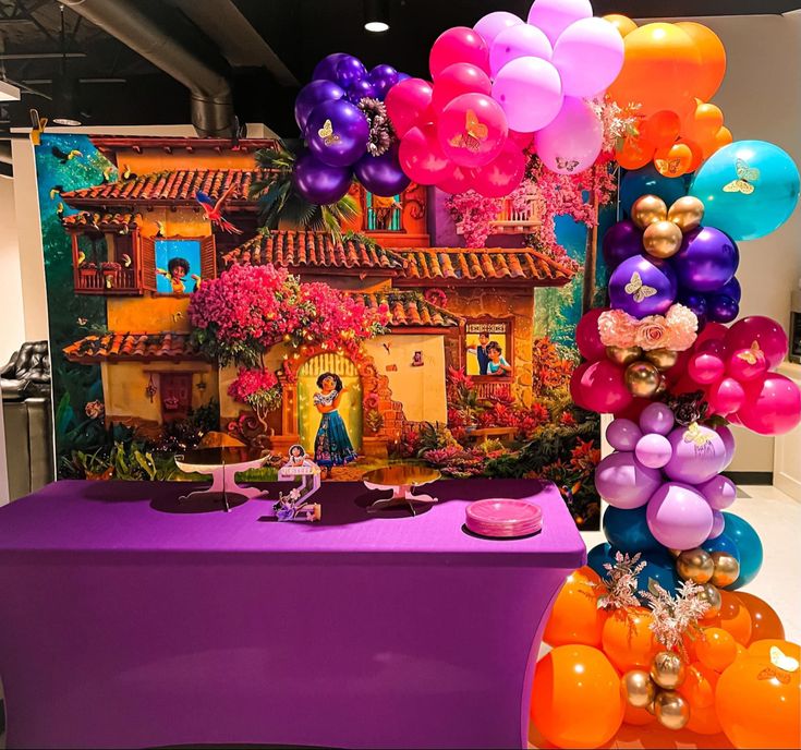 a table topped with lots of balloons next to a purple table cloth covered in pictures