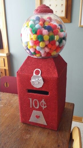 a gumball machine sitting on top of a wooden table next to a red box