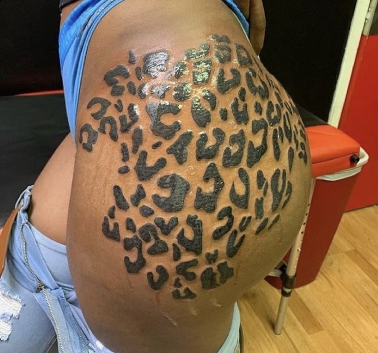 a woman with a tattoo on her back has a large leopard print on it's side