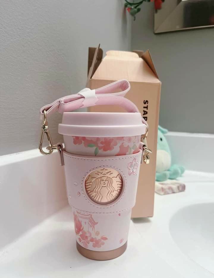 a pink starbucks cup shaped keychain sitting on top of a counter next to a box