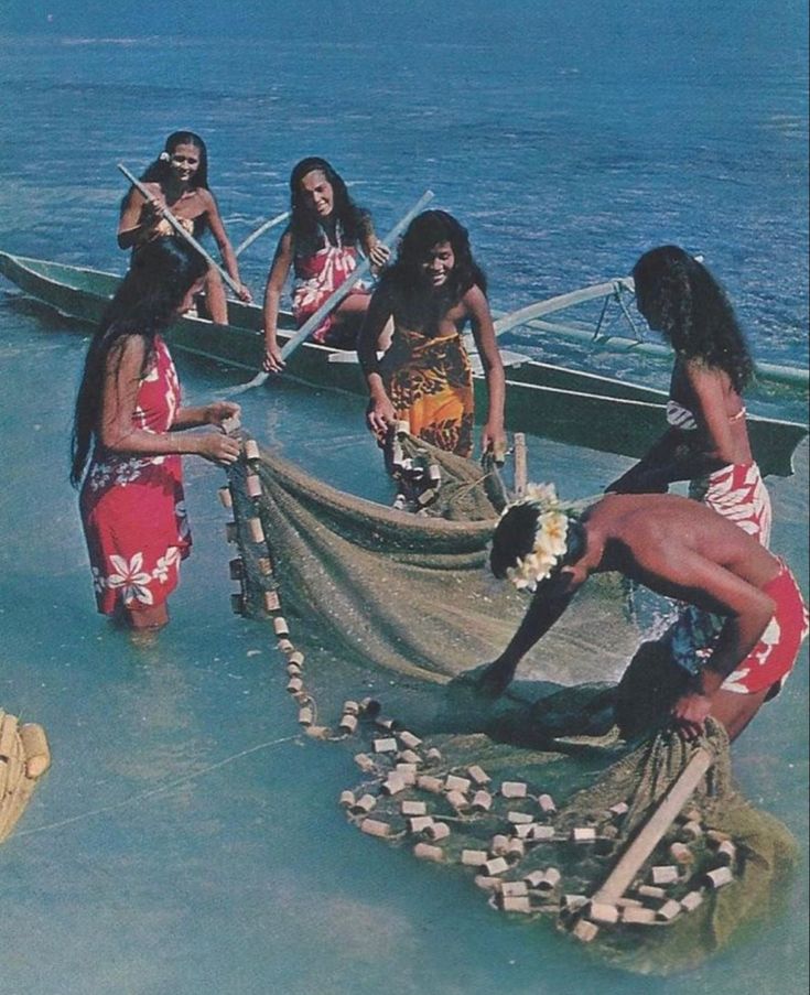 some people are standing in the water near a boat with a long net on it