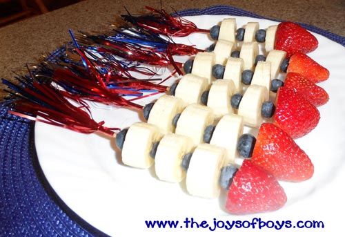 strawberries, bananas and blueberries are arranged on a plate with toothpicks