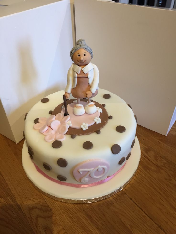 a cake decorated with an elderly woman figurine on top of the cake is next to a box