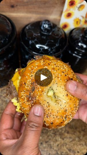 a person is holding a hamburger in front of some jars with jams on them