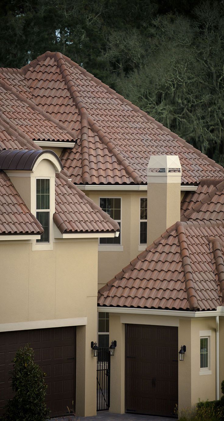 a large house with two garages and brown roof tiles on the front of it