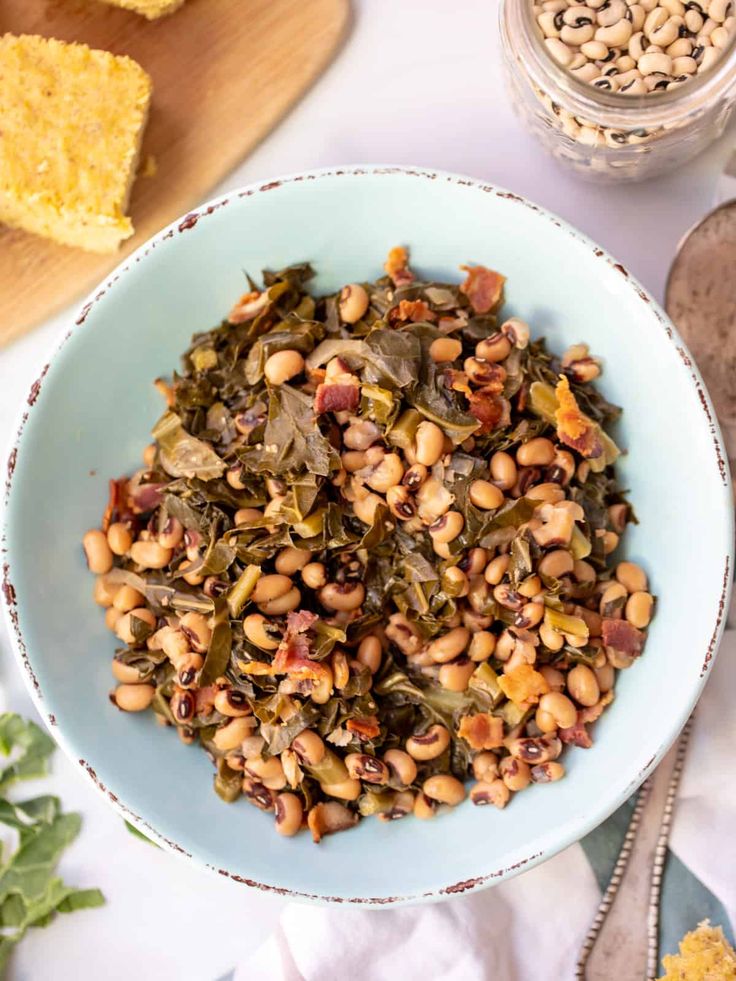 a bowl filled with beans and greens next to cornbreads