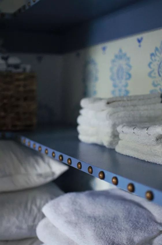 towels are stacked on top of each other in a room with blue and white wallpaper