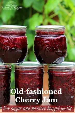 four jars filled with jam sitting on top of a wooden table