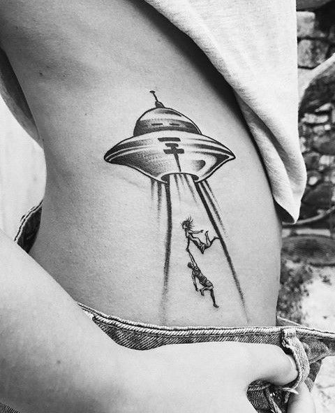 a woman with a tattoo on her stomach has an alien ship flying through the sky