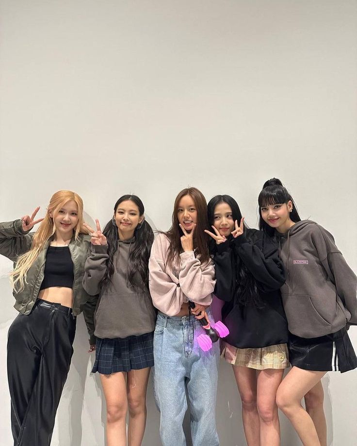 the girls are posing in front of a white wall with their hands up and smiling